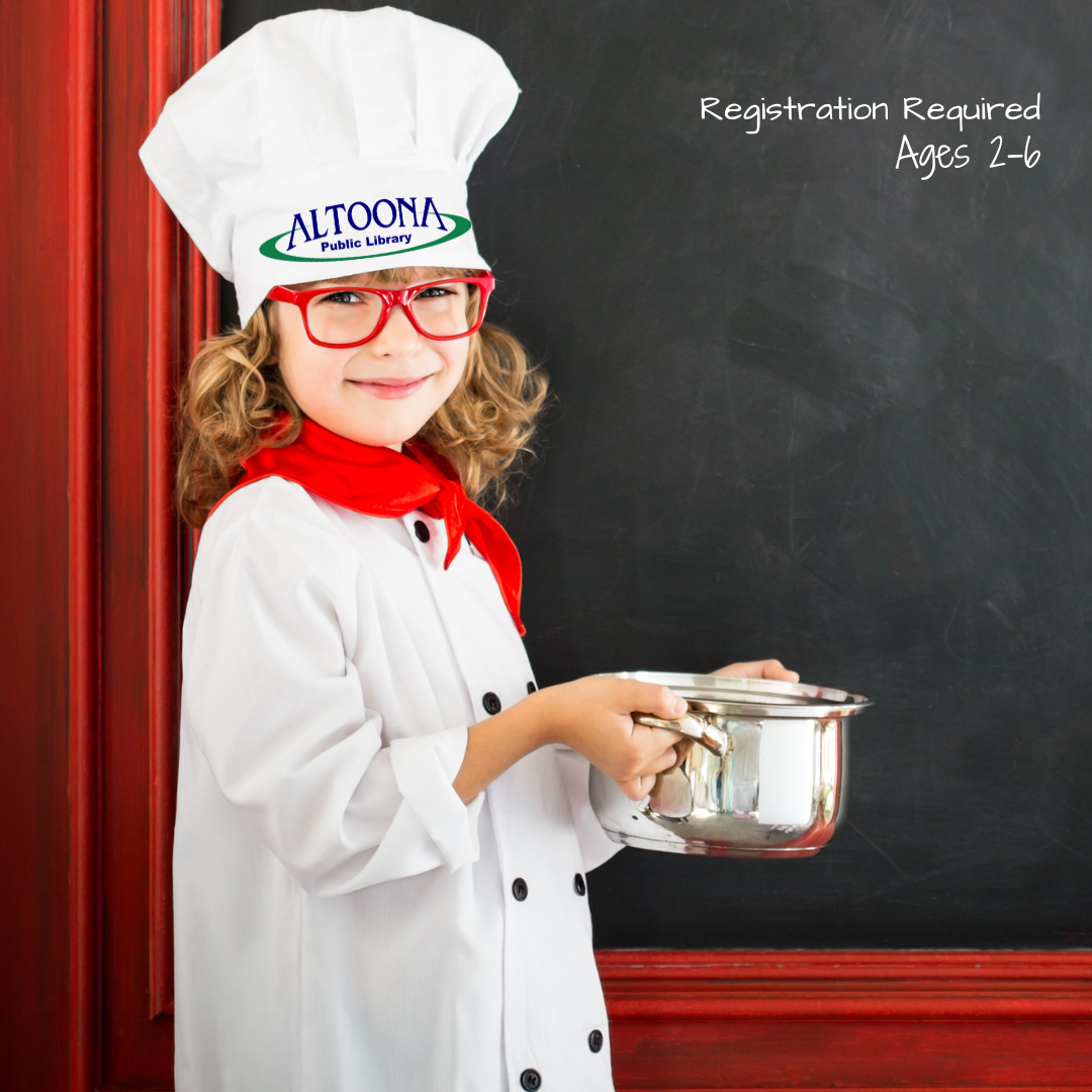 photo of child in chef's whites holding a pot in front of a chalkboard and red curtains
